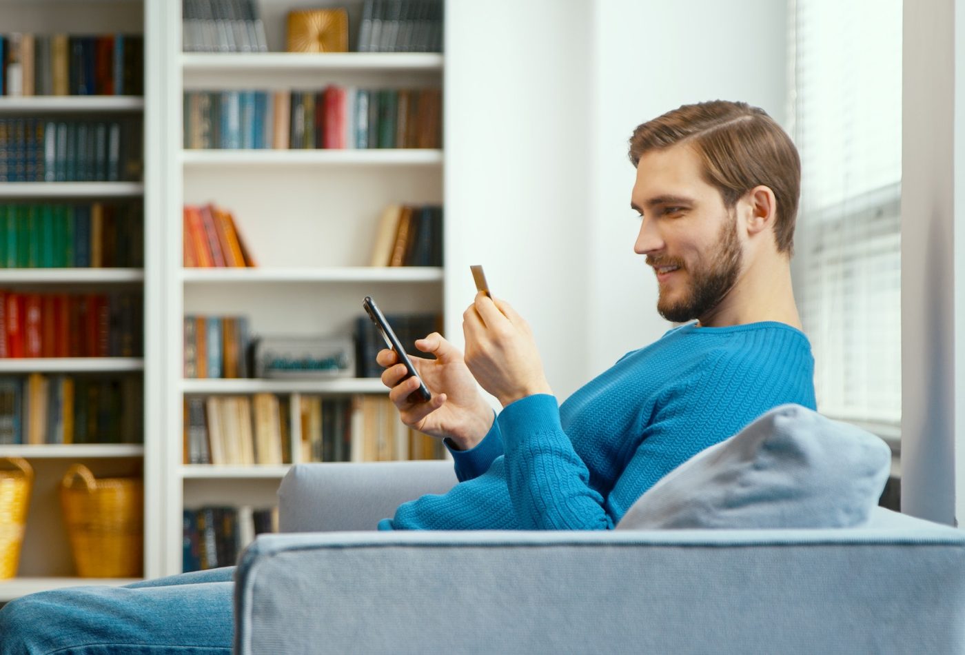 young-man-looks-at-bank-card-in-hand-and-enters-digits-to-smartphone.jpg